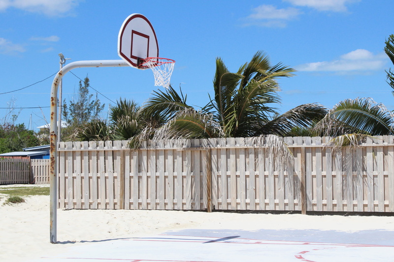 fence, basketball - ball, leisure activity, basketball - sport, mid-air, outdoors, cloud - sky, court, standalone, barrier, sky, tree, backboard, gray