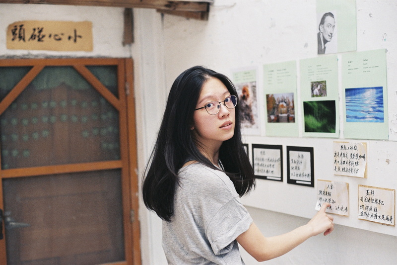 student, text, pointing, long hair, eyecontact, front, adult, bulletin, women, black hair, real people, glasses, standing, contemplation, hairstyle, woman
