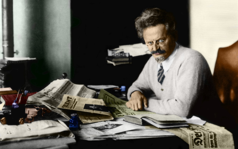 eyeglasses, looking at camera, sitting, mature adult, table, contemplation, historic, one person, the media, serious, paper currency, activity, indoors