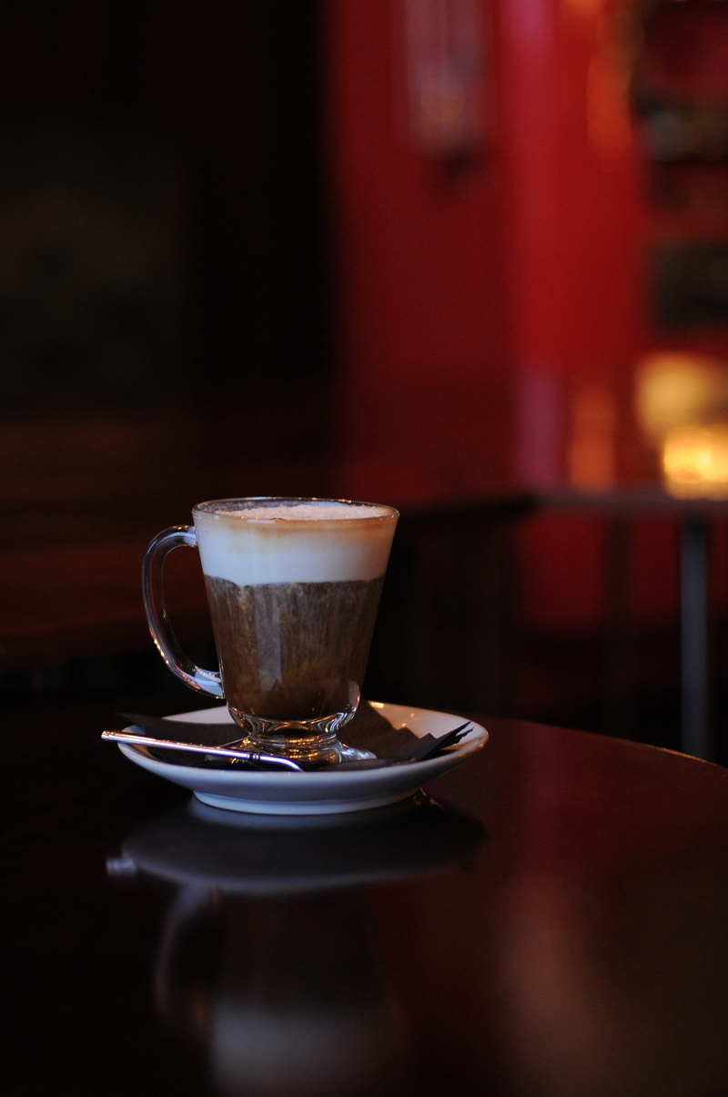 frothy drink, coffe, hot drink, turquoise, bar counter, glass, table, food and drink, plate rack, restaurant, coffee table, cafe, dark, drinking glass