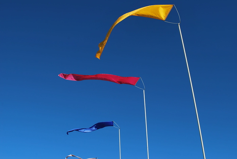 nature, wind, flying, sky, mid-air, clear sky, motion, sunny, flags, day, kite - toy, waving, primary colors, outdoors, no people, flag, freedom, multi colored