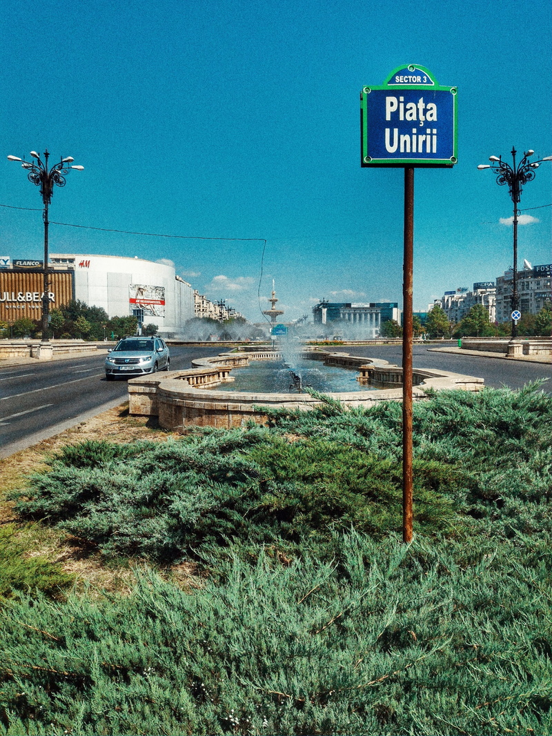 road, road sign, blue, street, sign, communication, clear sky, sky, 4K, text, city, grass, car, mode of transportation, guidance, buildings, romania, western script