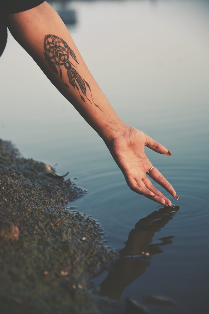 reaching, body part, dreamcatcher, human foot, female, woman, leisure activity, inked, outdoors, hand, real people, person, sky, lake, adult, people, human finger