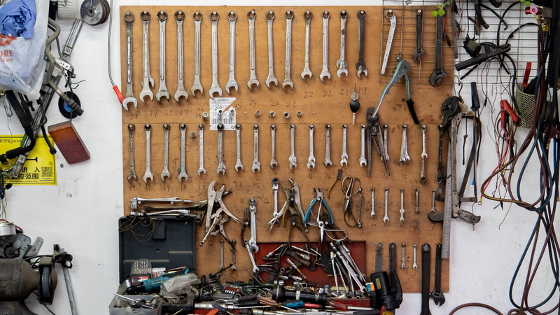 bicycle, large group of objects, indoors, tuen mun, workshop, table, video camera, shopping, camera, metal, repair shop, equipment, wiring, hong kong, hand tool