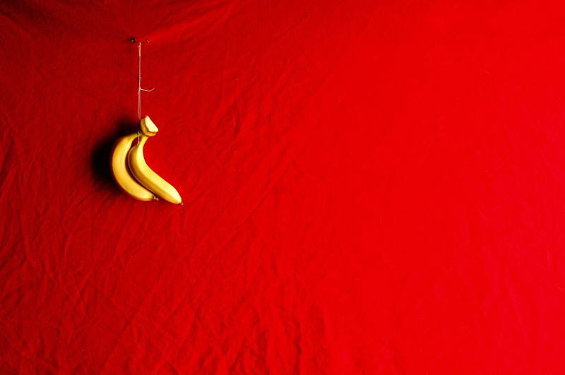 hanging, two objects, wood - material, food and drink, colored background, red background still life bananas fruit, studio shot, food, no people, still life