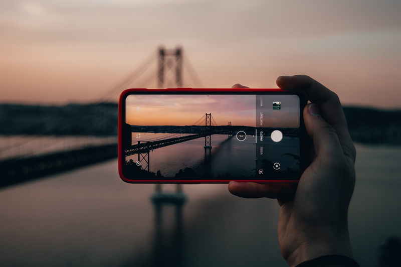 nature, real people, sunset, mobile phone, finger, human, portable information device, holding, car mirror, sky, hand, red, person, activity, portrait