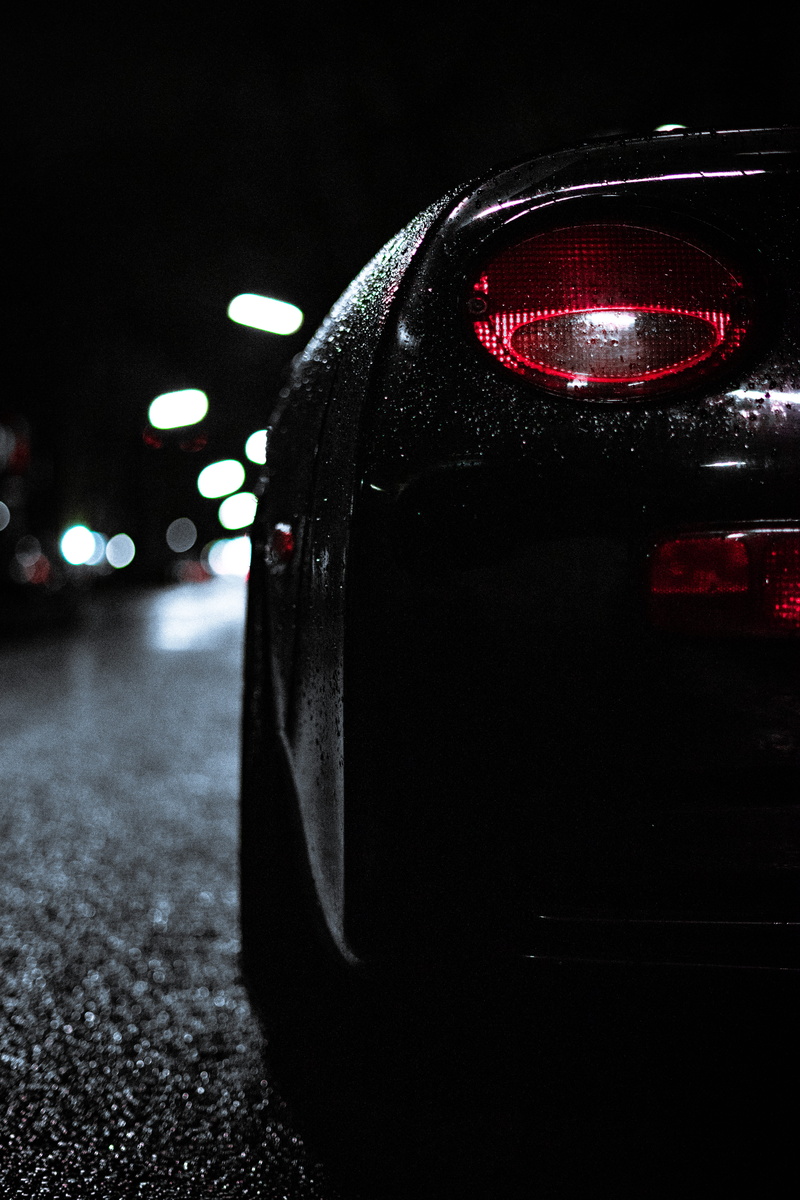 machine, black background, illuminated, land vehicle, indoors, light - natural phenomenon, headlight, street, car mirror, round, red, motor vehicle, mirror