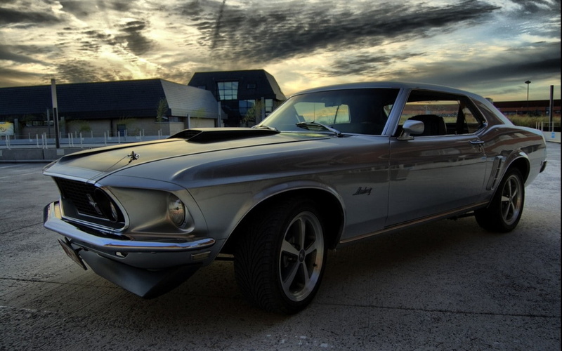outdoors, building exterior, vehicle, mode of transportation, day, sky, machine, land vehicle, Ford Mustang, stationary, Ford, street, cloud - sky, vintage car