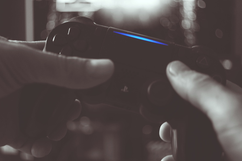 white, controller, lens flare, indoors, game, finger, unrecognizable person, hands, thumbs, close-up, playstation, real people, black, selective focus