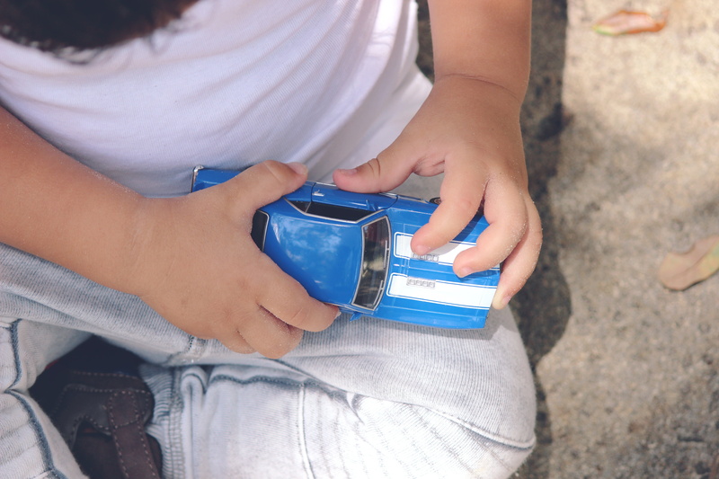vehicle, day, pavement, midsection, baby, kids toys, land, hand, front view, childhood, cast, human hand, holding, playing, concrete, game, blue, one person