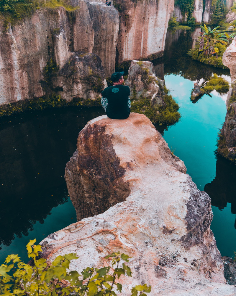 reflection, rock formation, beauty in nature, cave, men, sitting, tranquility, cove, facing, real people, promontory, one person, lifestyles, painting
