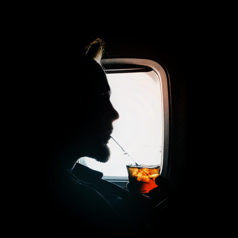 holding, glass, headshot, indoors, man, untitled, sipping, drink, male, young adult, window, aircraft, glasses, side view, mode of transportation, one person
