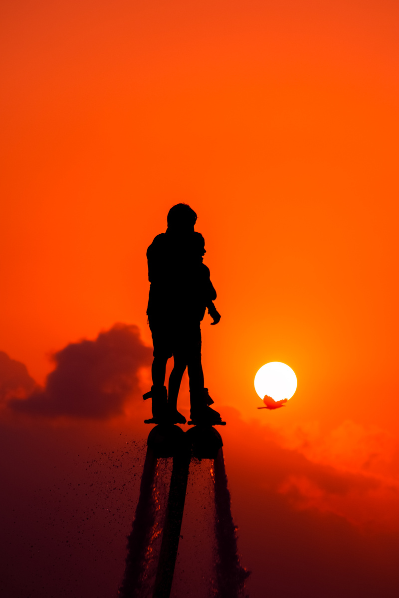 silhouette, lifestyles, leisure activity, jetpack, orange color, watersports, standing, scenics - nature, full length, flyboard, tranquility, beauty in nature