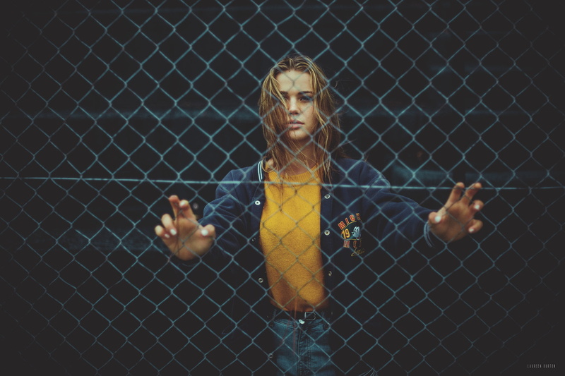 real people, blonde, men, close-up, full length, young adult, fence, blue clothing, day, denim, leisure activity, males, jacket, focus on foreground, casual clothing