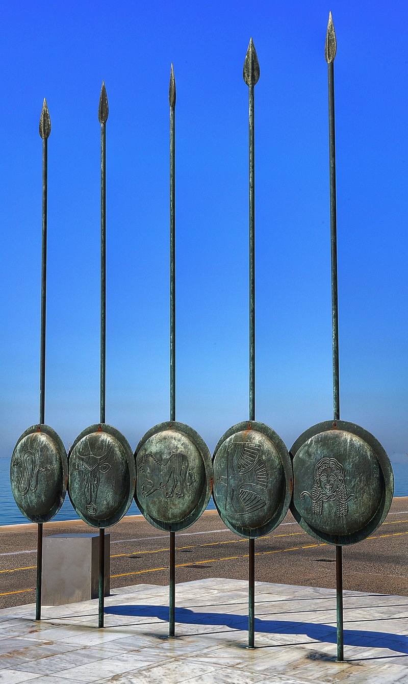 shields, sunlight, group of objects, side by side, outdoors, display, sky, metal, shadow, no people, nature, clear sky, architecture, spears, sculpture