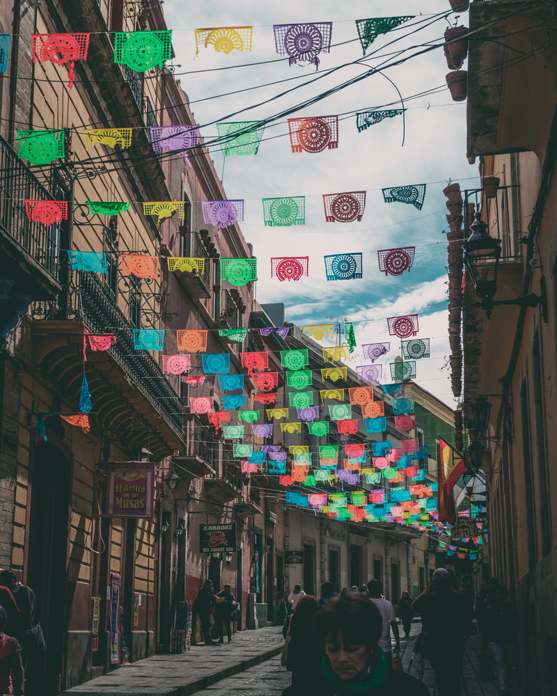 blue sky, non-western script, low angle view, retail, street, architecture, communication, guanajuato, group of people, multi colored, text, people, street photography