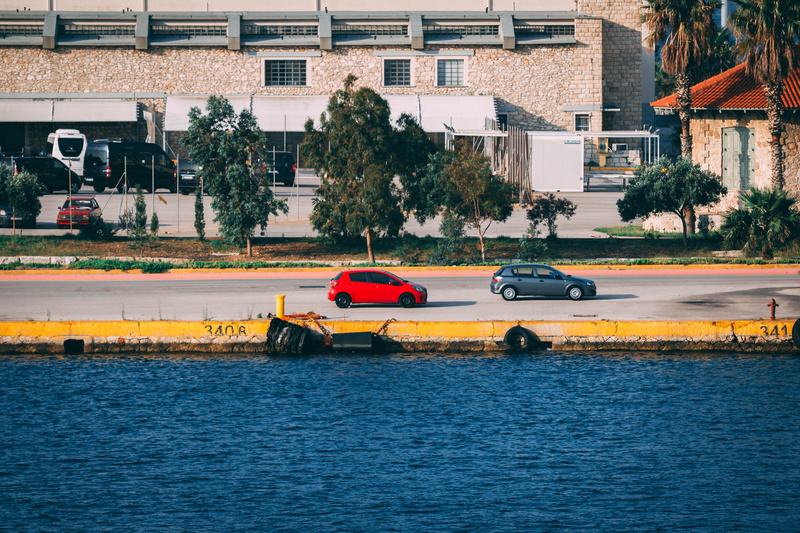motion, land vehicle, city, no people, built structure, motor vehicle, side, hatchbacks, vehicles, car, r, trees, wate, street, plant, building, waterfront