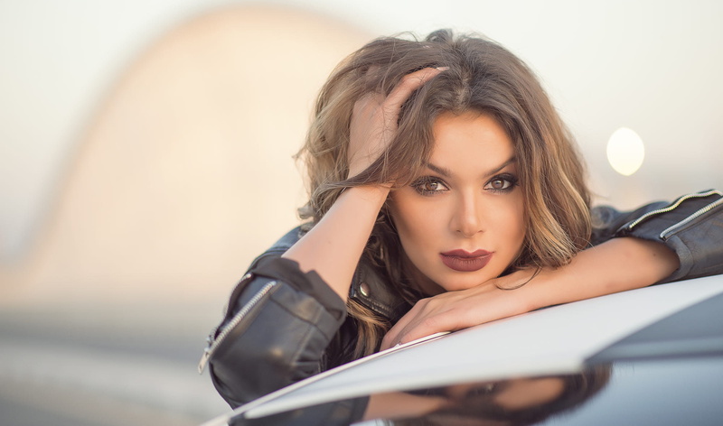 young women, hands in hair, bokeh, face, headshot, looking at camera, eyeshadow, land vehicle, car, motor vehicle, hairstyle, smirk, one person, long hair
