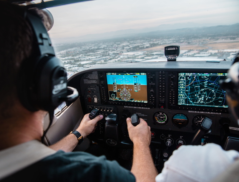 piloting, over the shoulder view, people, outdoors, aircraft, air Vehicle, boat Captain, water, flight, navigate, adult, building, pilot, one Person, technology