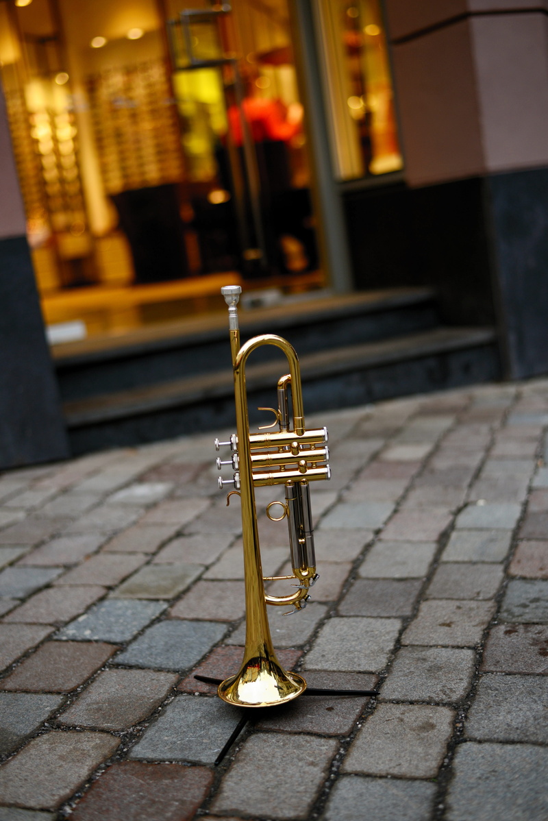 brass instrument, street music, gloss, no people, single object, outdoors, footpath, building exterior, music, musical instrument, gold colored, cobblestone