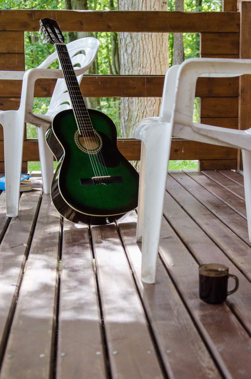 outdoor, musical instrument string, guitar, floor, railing, table, playing, day, coffee cup, porch, instrument, furniture, musical instrument, vacation