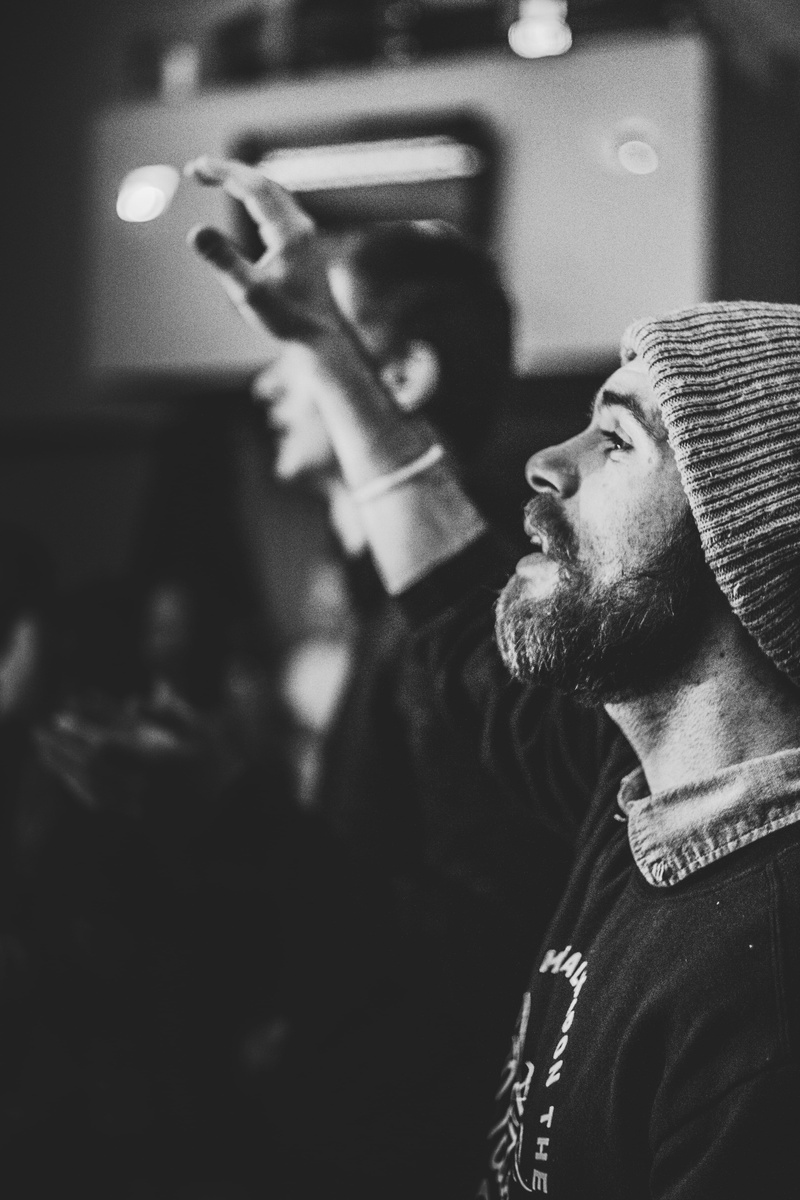 facial hair, sing, waist up, apparel, church, worship, cap, headshot, focus on foreground, musical instrument, service, beard, person, men, real people