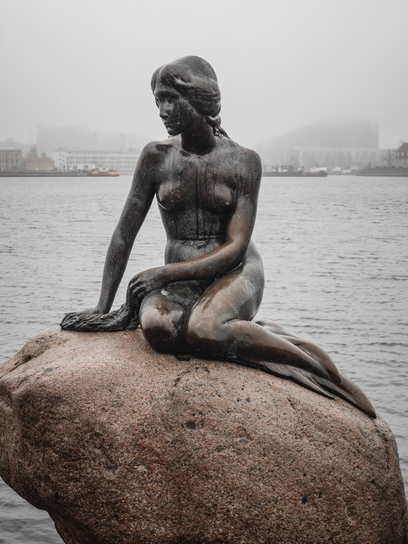 sky, architecture, outdoors, built structure, religion, landmark, day, copenhagen, travel, human representation, solid, sculpture, denmark, mermaid, statue