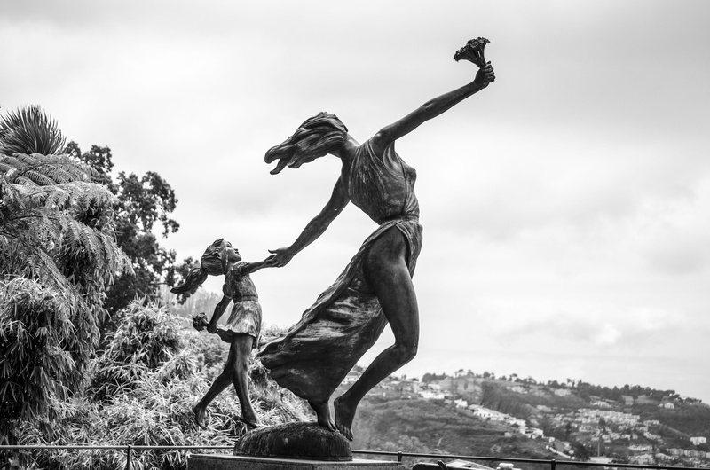 human arm, sky, mid-air, statue, day, women, male likeness, human representation, architecture, monument, the statue of, tree, woman, full length, sculpture