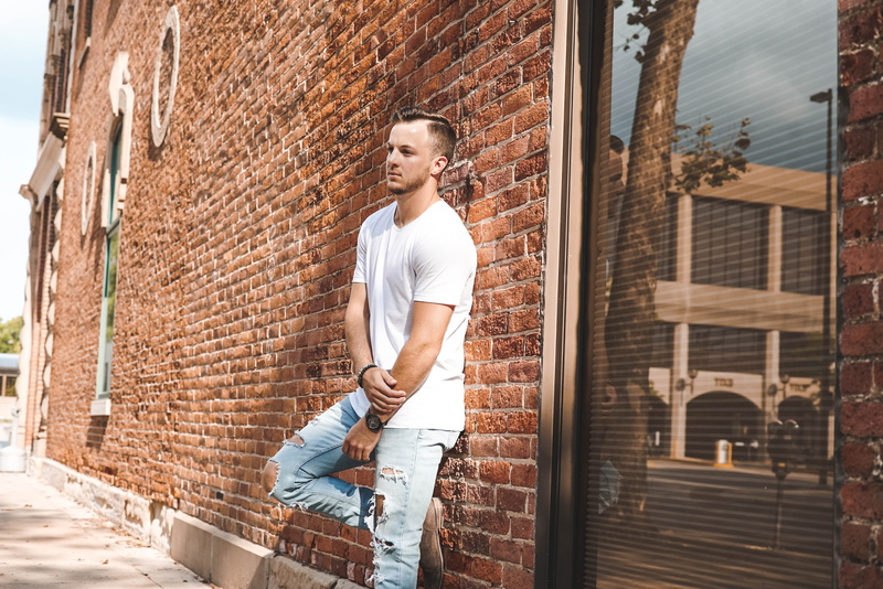 building, jeans, casual clothing, young adult, 4K, leaning, denim, man, front, wall, building exterior, architecture, daytime, outdoors, brick, leisure activity