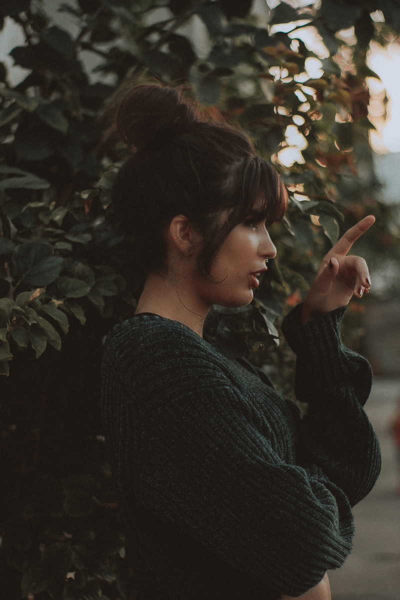 pierced nose, young women, profile view, tree, pullover, side view, leaf, lifestyles, waist up, profile, casual clothing, standing, plant part, hairbun