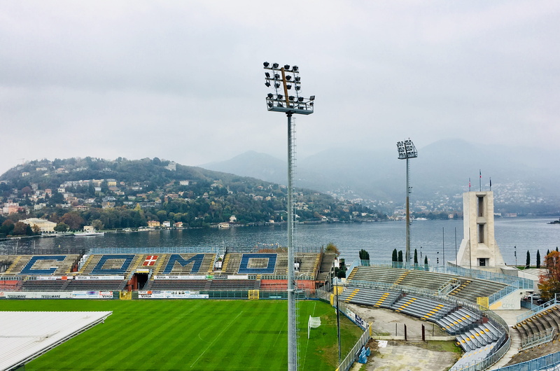 building, amphitheatre, team sport, floodlight, large group of people, crowd, real people, tower, stadium, lighting equipment, sport, built structure, field