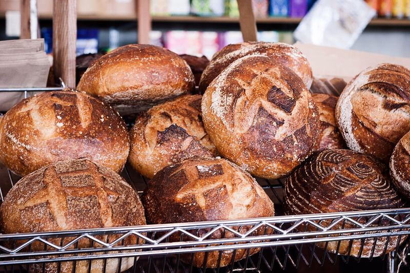 large group of objects, food and drink, bloomer, fresh, tray, strandfield, focus on foreground, still life, crust, bakery, warm, indoors, sourdough, ready-to-eat