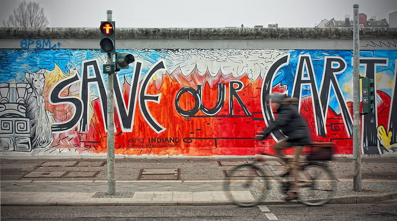 day, republic, person, near, adult, road, sign, graffity, outdoors, mode of transportation, east side gallery, people, painting, blurred motion, lifestyles