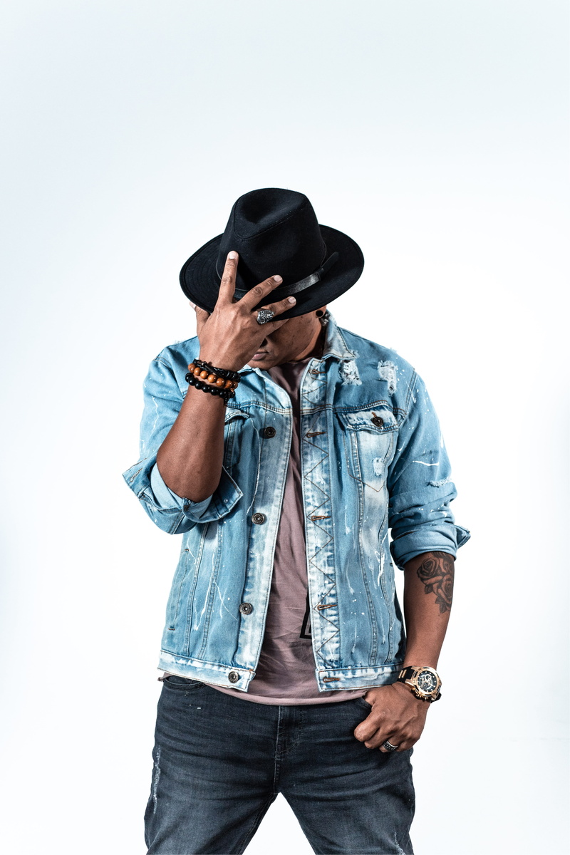 buckle, man, black, apparel, sombrero, clothing, brick, one person, harmonica, denim, human face, indoors, jacket, casual clothing, fashion, coat, white background