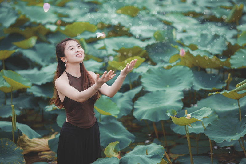 nice, west lake, young adult, focus on foreground, leaves, outdoors, plant, three quarter length, smiling, gesturing, 5K, vietnam, lotus, hanoi, lifestyles