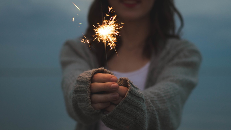 hand, adult, firework, sweater, holding, front view, casual clothing, glowing, sparks, burning, women, blurred motion, focus on foreground, celebration
