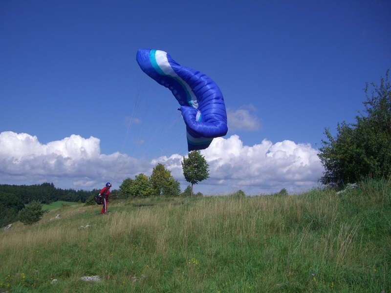 cloud - sky, lifestyles, plant, grass, castle hill, floating sailing, landscape, field, day, paraglider, paragliding, real people, one person, land, outdoors
