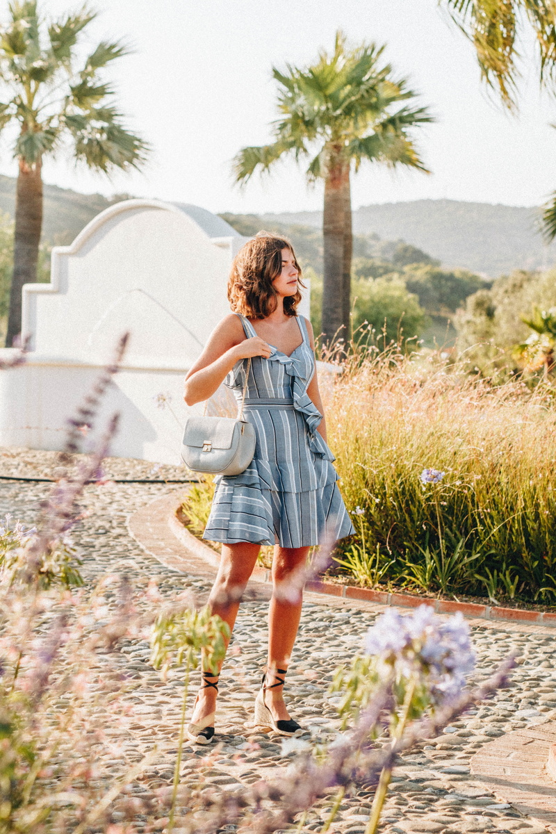 sunlight, sundress, sling, fashion, day, hair, woman, outdoors, plant, story, one person, bag, sleeveless, women, tree, dress, standing, hairstyle, real people