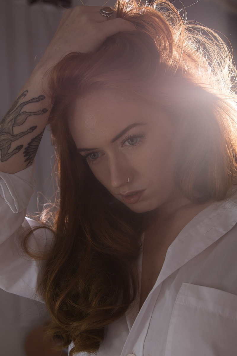 front view, headshot, portrait, hand in hair, body part, hairstyle, model, one person, shirt, long hair, contemplation, tattoo, beautiful people, redhead