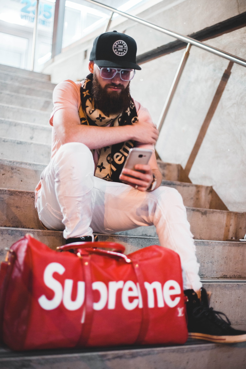 leather, glasses, apparel, vuitton, communication, clothing, holding, one person, phone, electronics, staircase, young adult, portrait, photo, sitting