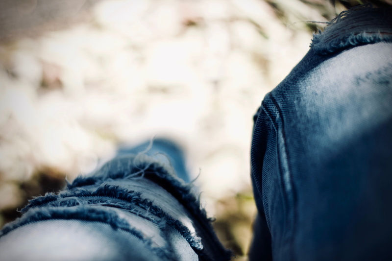 tattered jeans, hood - clothing, selective focus, focus on foreground, jeans, 5K, warm clothing, people, body part, midsection, trousers, ripped, leisure activity
