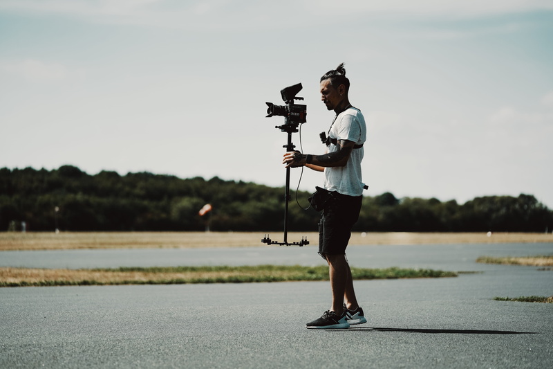 side view, professional, using, tripod, footwear, animal, bird, shorts, full length, day, weaponry, sky, red, gun, photographer, real people, one person