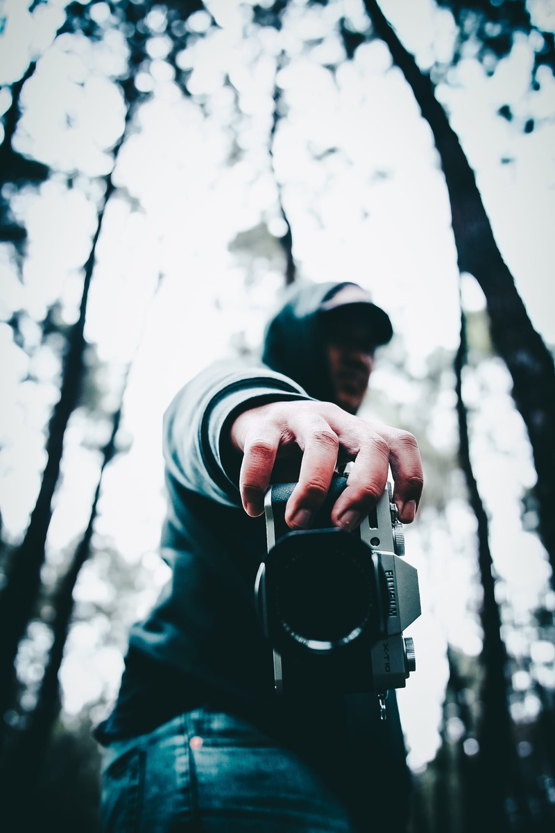 day, person, human hand, holding, photographic equipment, camera, leisure activity, finger, photography, tree, outdoors, activity, camera lens, digital single-lens reflex camera