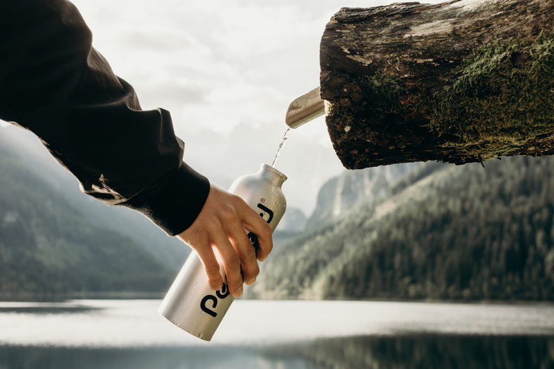 gray, tumbler, catching, hanging, focus on foreground, near, close-up, 5K, holding, human hand, sky, nozzle, non-urban scene, adult, lake, outdoors, leisure activity