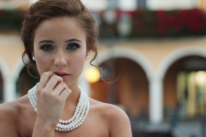 portrait, looking at viewer, architecture, front view, brown hair, beauty, jewelry, contemplation, hair, pearl necklace, finger on lips, one person, necklace