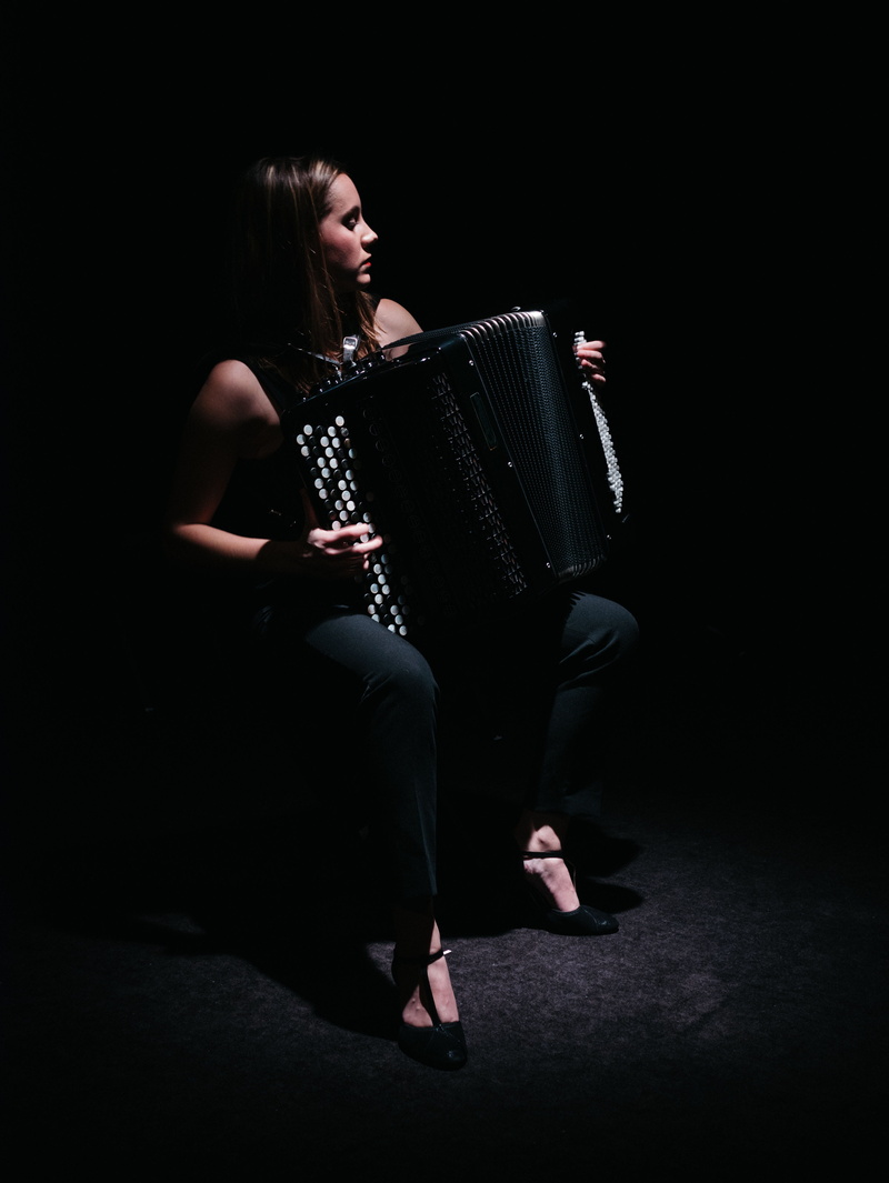 studio shot, human, spectacle, full length, footwear, dark, playing, patio, black color, sleeve, hairstyle, neck, musical instrument, accordeonist, accordeon