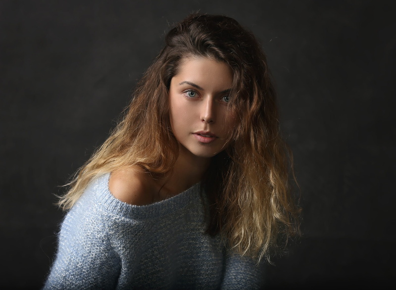 black background, face, lifestyles, front view, bare shoulders, studio shot, portrait, headshot, young adult, sweater, hairstyle, simple background, tanned