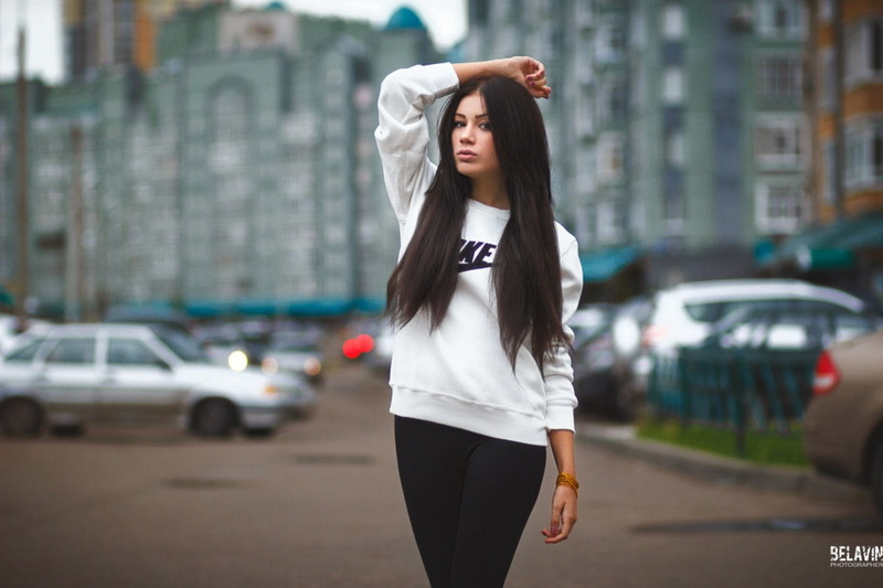 car, watermarked, 720P, model, straight hair, bokeh, building, red nails, painted nails, women outdoors, brunette, black pants, standing, sweater, pants