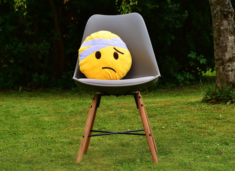 pillow, human representation, green color, outdoors, field, front or back yard, ill, land, plush, day, nature, injured, get well soon, toy, chair, emoji