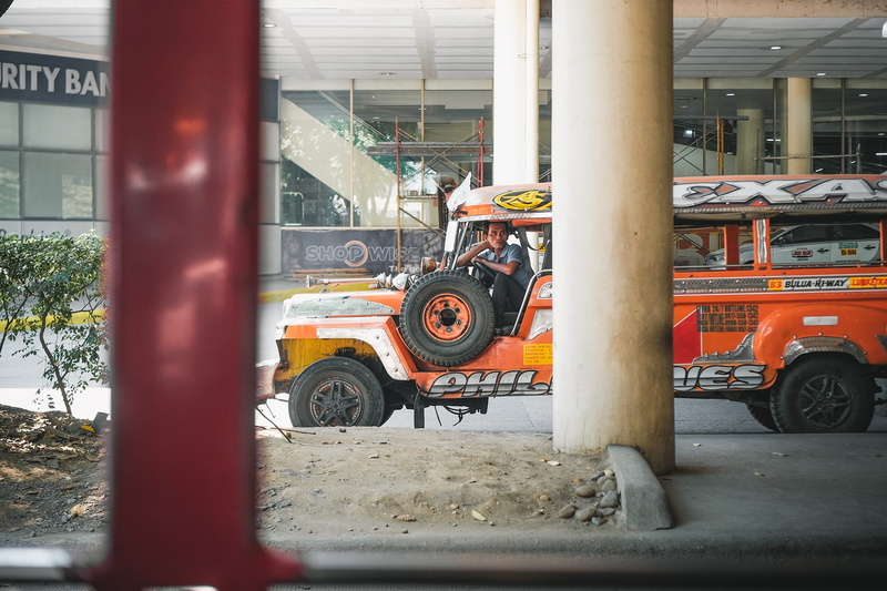 motor vehicle, city, road, outdoors, stationary, built structure, architecture, street, land vehicle, jeepney, incidental people, public transportation